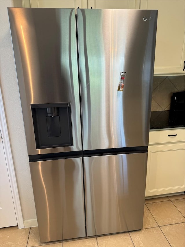 kitchen featuring light tile patterned floors, white cabinetry, and stainless steel fridge