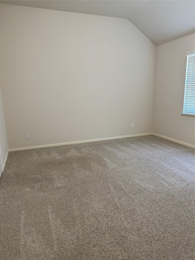 carpeted spare room featuring lofted ceiling