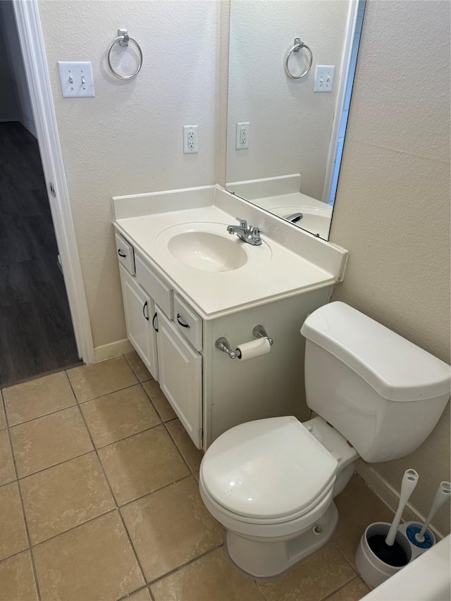 bathroom with toilet, vanity, and tile patterned flooring