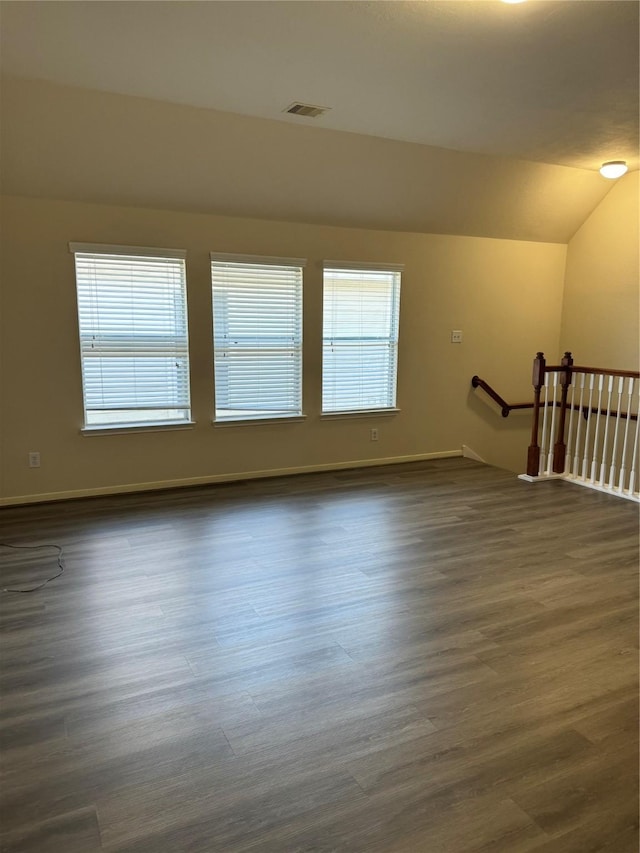 empty room with vaulted ceiling and dark hardwood / wood-style floors