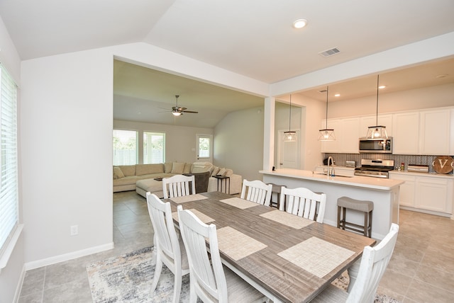 tiled dining area featuring sink, ceiling fan, and vaulted ceiling