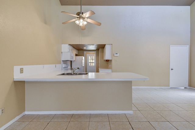 kitchen with light tile patterned floors, white appliances, kitchen peninsula, and a high ceiling