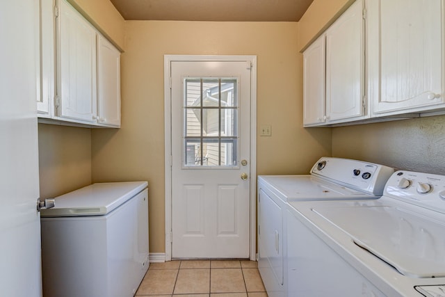 clothes washing area featuring cabinets, light tile patterned floors, and washing machine and clothes dryer