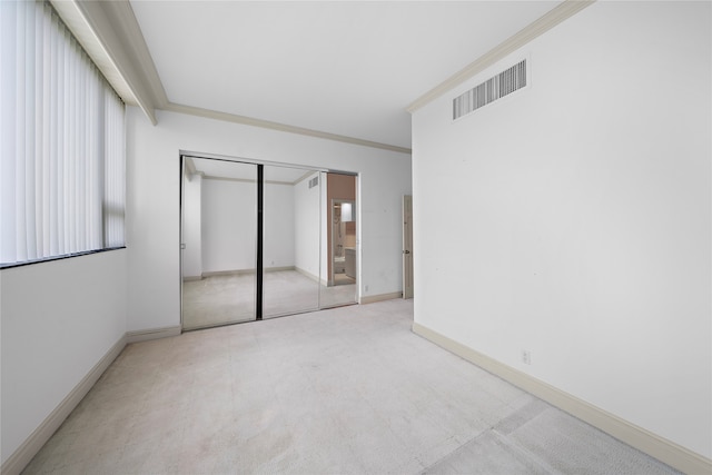 unfurnished bedroom featuring light colored carpet, a closet, and ornamental molding