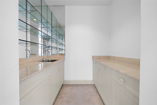 bar with light carpet, white cabinets, light stone counters, and sink