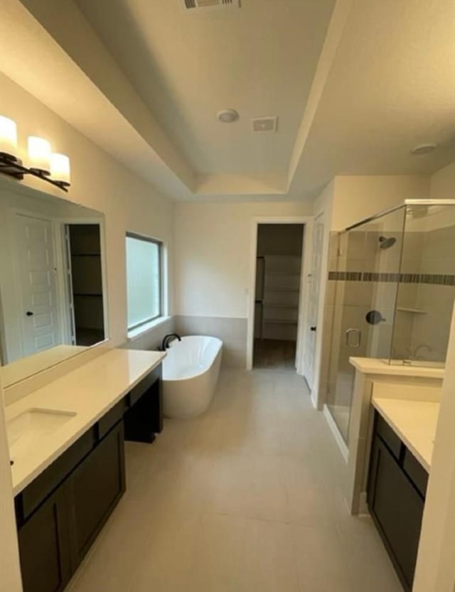 bathroom featuring shower with separate bathtub, vanity, and a raised ceiling