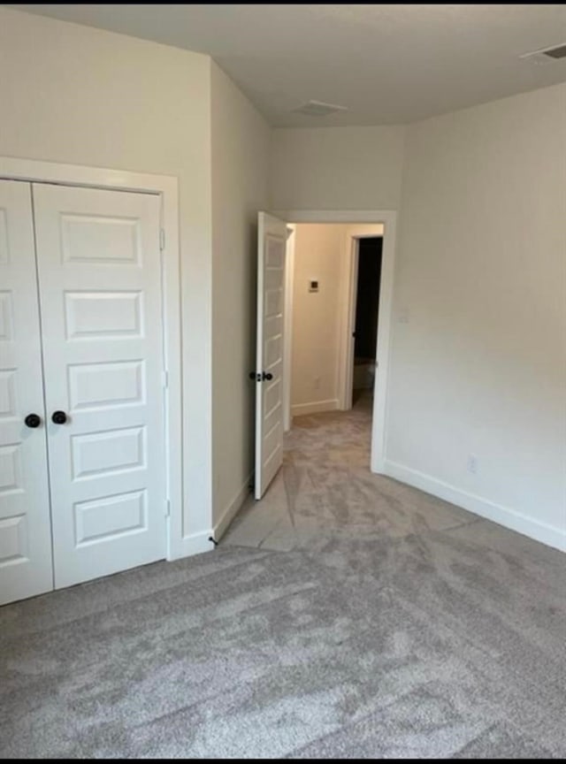 unfurnished bedroom with light colored carpet and a closet