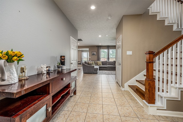 hallway featuring a textured ceiling and light tile flooring