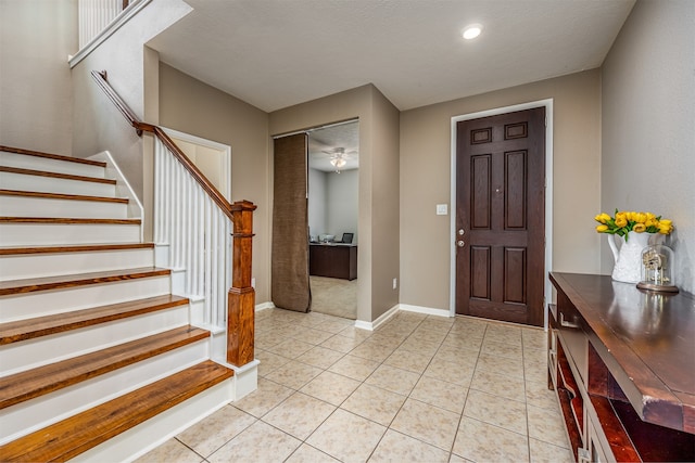 tiled foyer entrance with a textured ceiling and ceiling fan