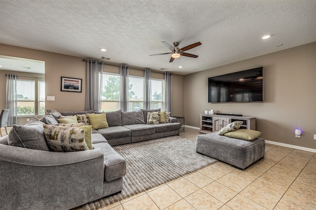 living room with a textured ceiling, ceiling fan, light tile flooring, and a wealth of natural light