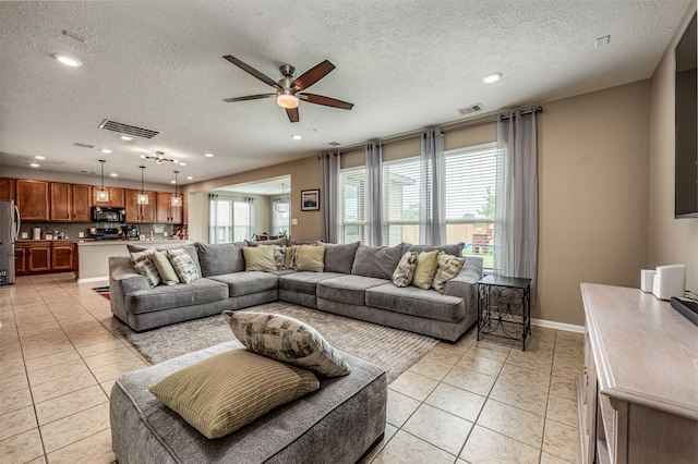 living room with ceiling fan, light tile flooring, and a textured ceiling