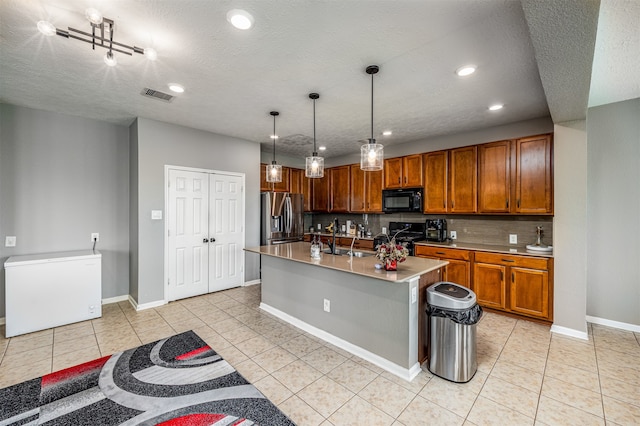 kitchen with black appliances, a kitchen island with sink, pendant lighting, sink, and light tile floors