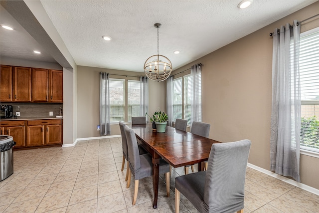 tiled dining area featuring an inviting chandelier, a textured ceiling, and a wealth of natural light