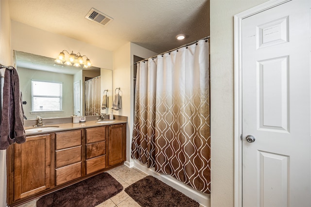 bathroom featuring double vanity, tile flooring, and a textured ceiling