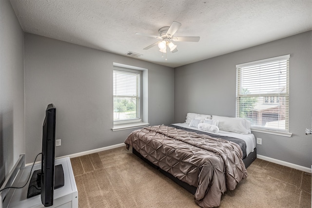 carpeted bedroom with ceiling fan and a textured ceiling