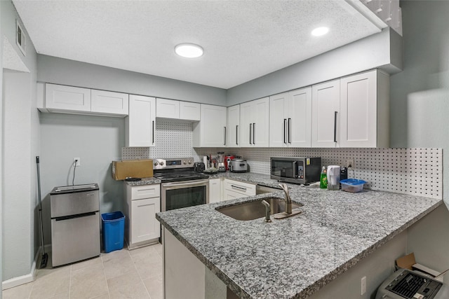 kitchen with stone counters, kitchen peninsula, sink, appliances with stainless steel finishes, and white cabinetry