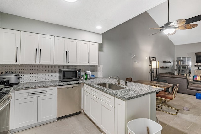 kitchen with kitchen peninsula, appliances with stainless steel finishes, white cabinets, and sink