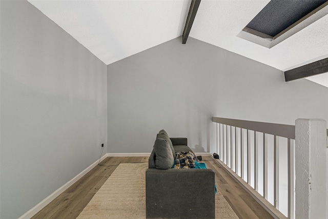 additional living space with hardwood / wood-style floors and lofted ceiling with beams