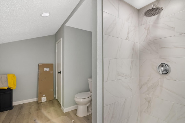 bathroom featuring hardwood / wood-style flooring, toilet, and tiled shower