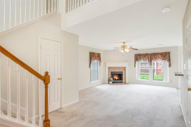 unfurnished living room featuring ceiling fan, a towering ceiling, and light colored carpet