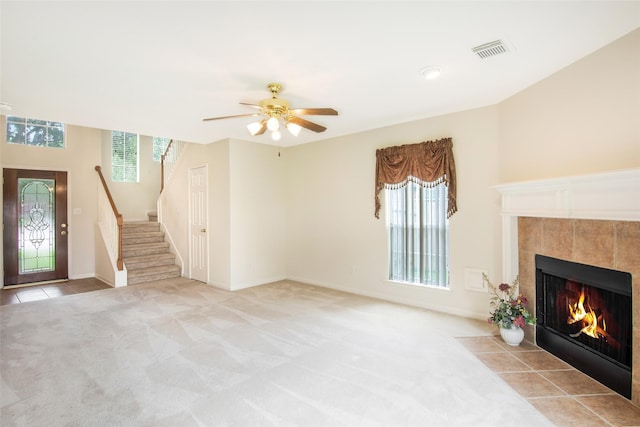 living room featuring light colored carpet, ceiling fan, a healthy amount of sunlight, and a tiled fireplace