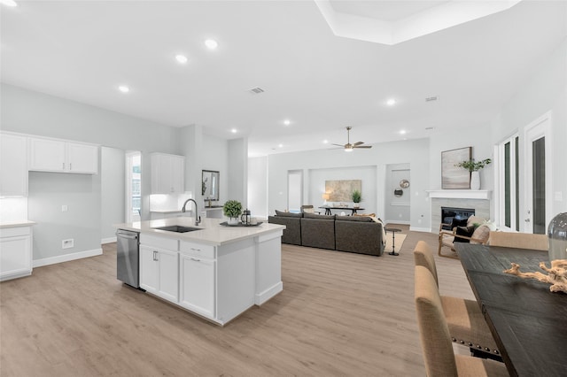 kitchen featuring white cabinetry, sink, ceiling fan, an island with sink, and a fireplace