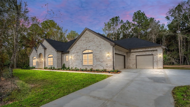 french provincial home with a garage and a lawn