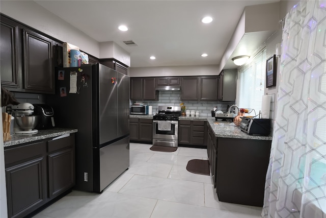 kitchen featuring stainless steel appliances, stone counters, backsplash, light tile floors, and sink