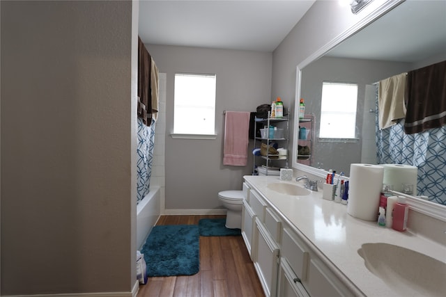 full bathroom with vanity with extensive cabinet space, toilet, hardwood / wood-style floors, shower / tub combo, and double sink