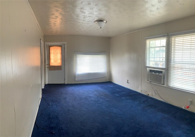 carpeted empty room featuring a textured ceiling, plenty of natural light, and cooling unit