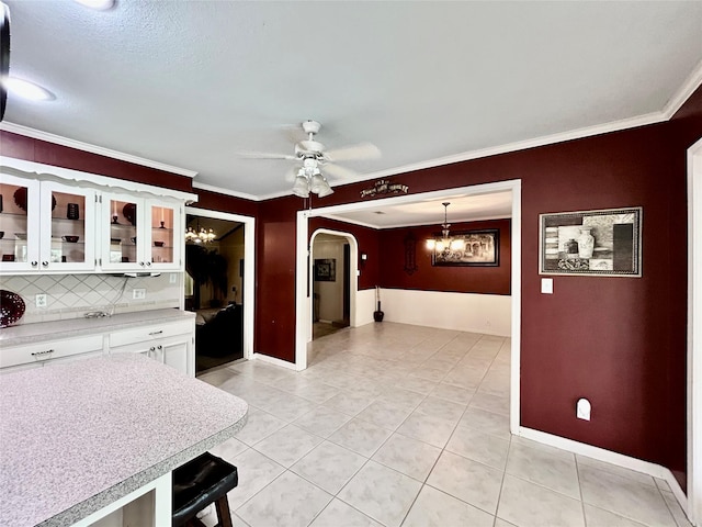 kitchen with arched walkways, glass insert cabinets, hanging light fixtures, light countertops, and white cabinetry