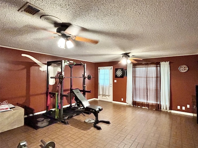 workout room with a textured ceiling, a ceiling fan, visible vents, and baseboards