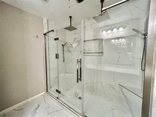 full bath with marble finish floor, a marble finish shower, baseboards, and a textured ceiling