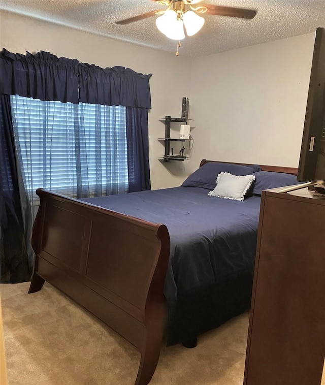 bedroom with a textured ceiling, a ceiling fan, and light colored carpet