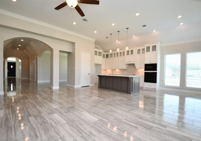 kitchen featuring hanging light fixtures, a large island with sink, lofted ceiling, white cabinets, and black appliances