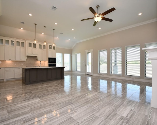 kitchen featuring ceiling fan, a kitchen island with sink, black appliances, decorative light fixtures, and white cabinetry