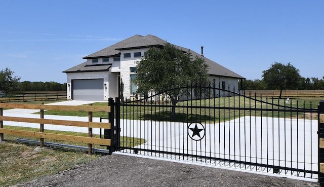 view of gate with a yard, a rural view, and a garage