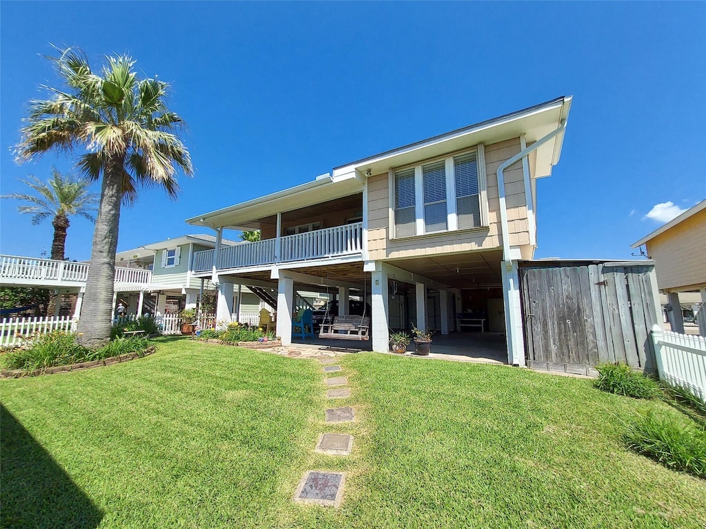 back of house with a lawn and a balcony