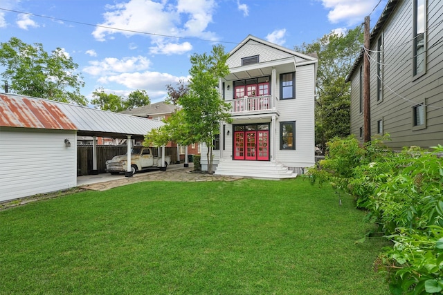 back of property featuring a yard, a carport, and a balcony