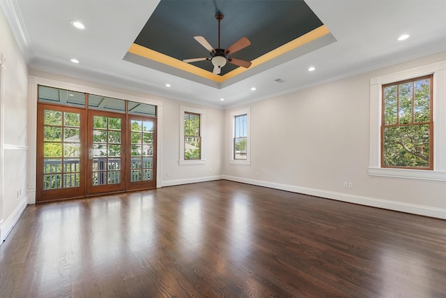 spare room featuring crown molding, a tray ceiling, dark hardwood / wood-style flooring, and ceiling fan