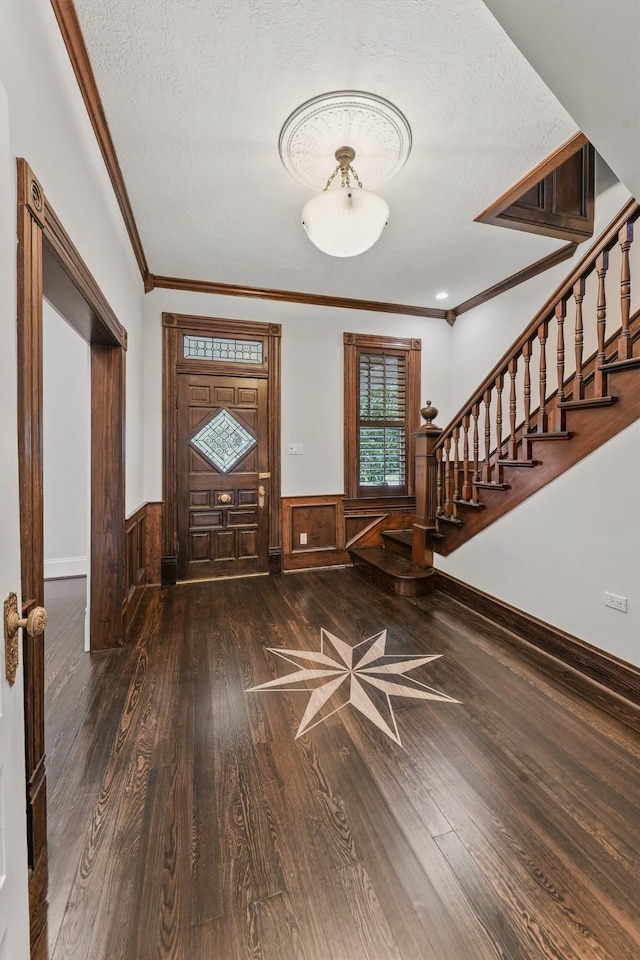 foyer featuring crown molding, dark wood-type flooring, and a textured ceiling