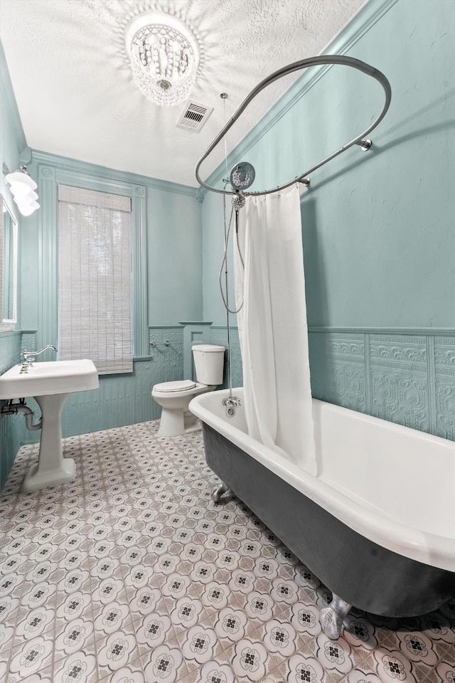 full bathroom featuring a textured ceiling, shower / bath combo, ornamental molding, and toilet