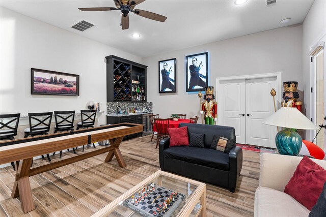 rec room featuring wood-type flooring, ceiling fan, and indoor bar