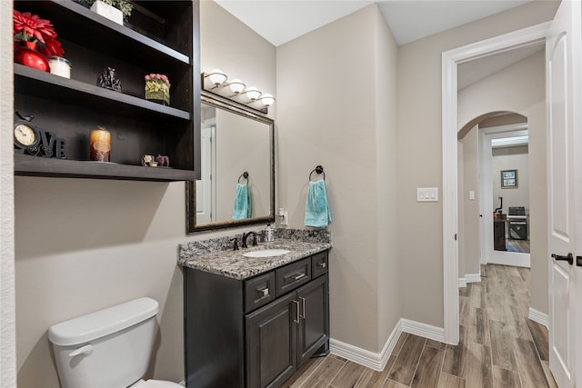 bathroom with wood-type flooring, vanity, and toilet