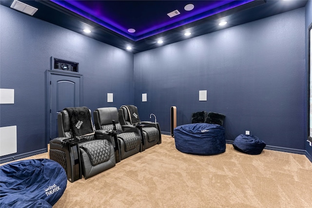 carpeted cinema room with a raised ceiling