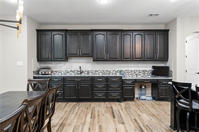 kitchen featuring tasteful backsplash, sink, and light wood-type flooring