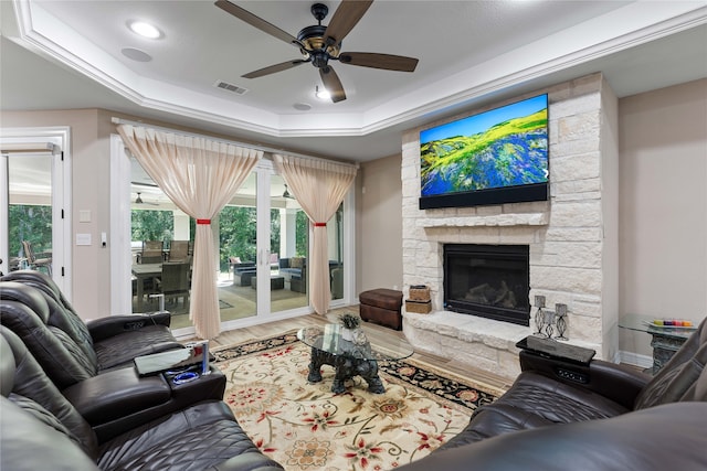 living room featuring hardwood / wood-style flooring, ceiling fan, a fireplace, ornamental molding, and a raised ceiling