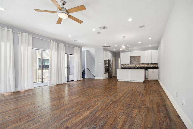 unfurnished living room with sink, dark hardwood / wood-style flooring, and ceiling fan with notable chandelier