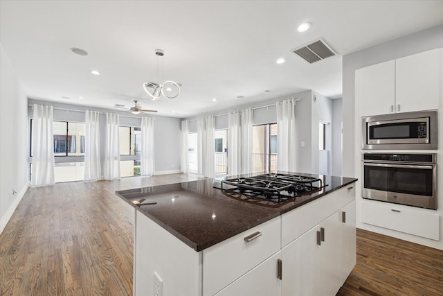 kitchen with dark hardwood / wood-style floors, ceiling fan, a center island, white cabinets, and appliances with stainless steel finishes