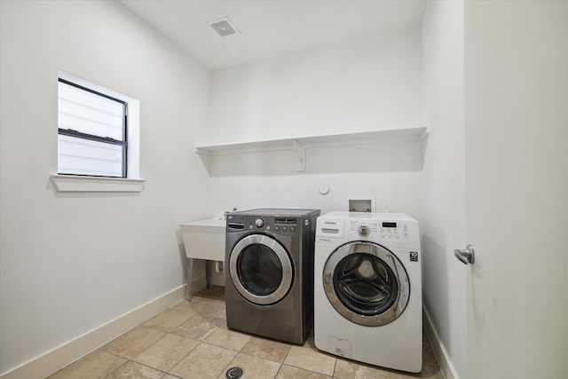 clothes washing area with separate washer and dryer, light tile flooring, and washer hookup